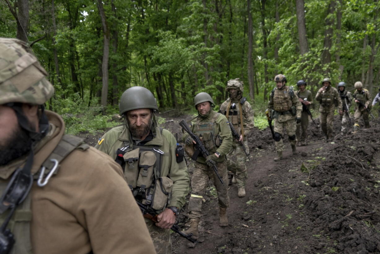 Ukrainian servicemen walk in the forest near a recently retaken village, north of Kharkiv, east Ukraine, Sunday, May 15, 2022.