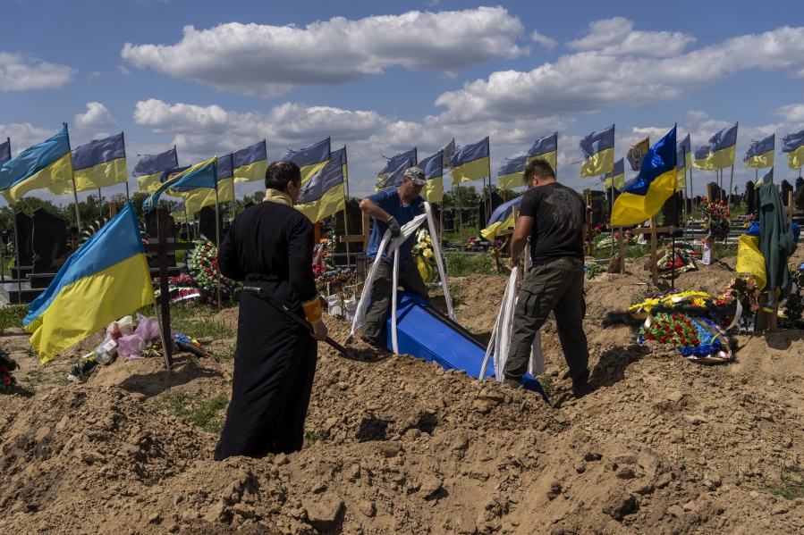 Undertakers lower the coffin of Ukrainian serviceman Oleksander Matyukhin, 32, in Kharkiv, eastern Ukraine, Monday, May 23, 2022.