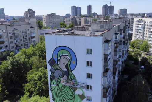 A worker paints a "Saint Javelin", a Virgin Mary holding an American-made anti-tank missile, in Kyiv, Ukraine, Tuesday, May 24, 2022. No matter where they live, the 3-month-old war never seems to be far away for Ukrainians. Those in towns and villages near the front lines hide in basements from constant shelling, struggling to survive with no electricity or gas -- and often no running water.