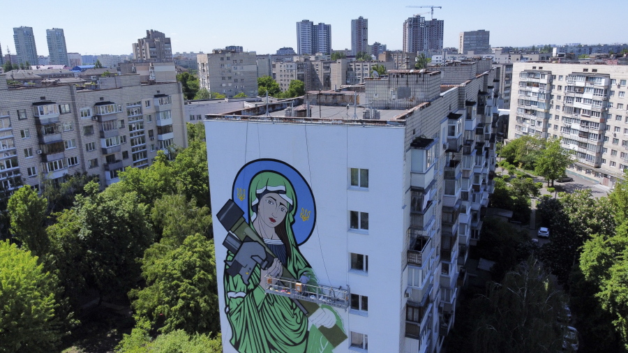 A worker paints a "Saint Javelin", a Virgin Mary holding an American-made anti-tank missile, in Kyiv, Ukraine, Tuesday, May 24, 2022. No matter where they live, the 3-month-old war never seems to be far away for Ukrainians. Those in towns and villages near the front lines hide in basements from constant shelling, struggling to survive with no electricity or gas -- and often no running water.