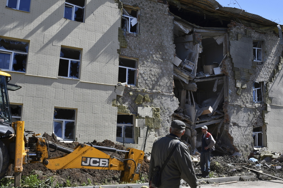 Men stand next to an apartment building damaged by Russian shelling in Bakhmut, Donetsk region, Ukraine, Thursday, May 12, 2022.