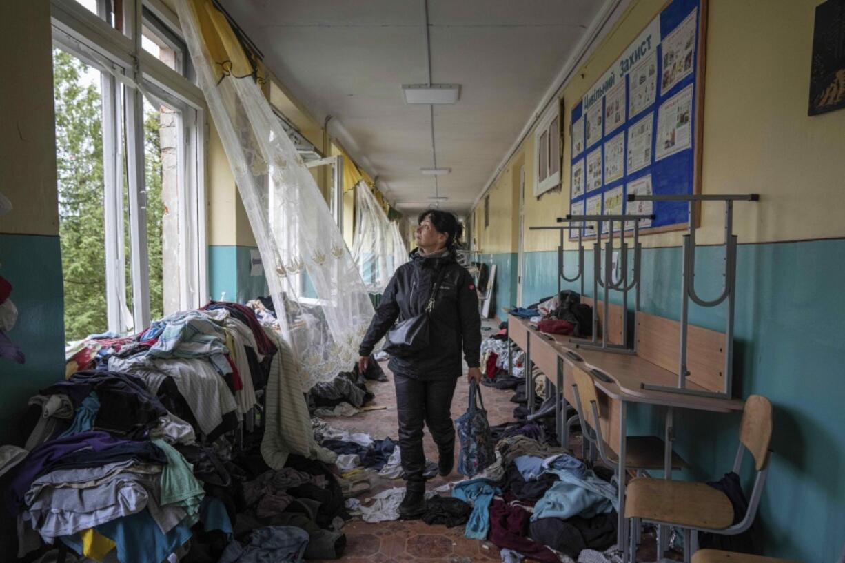 FILE - School official Iryna Homenko walks in the hall of a school damaged by an airstrike from Russian forces in Chernihiv, Ukraine, Wednesday, April 13, 2022. In Chernihiv alone, the city council said only seven of the city's 35 schools were unscathed. Three were reduced to rubble.