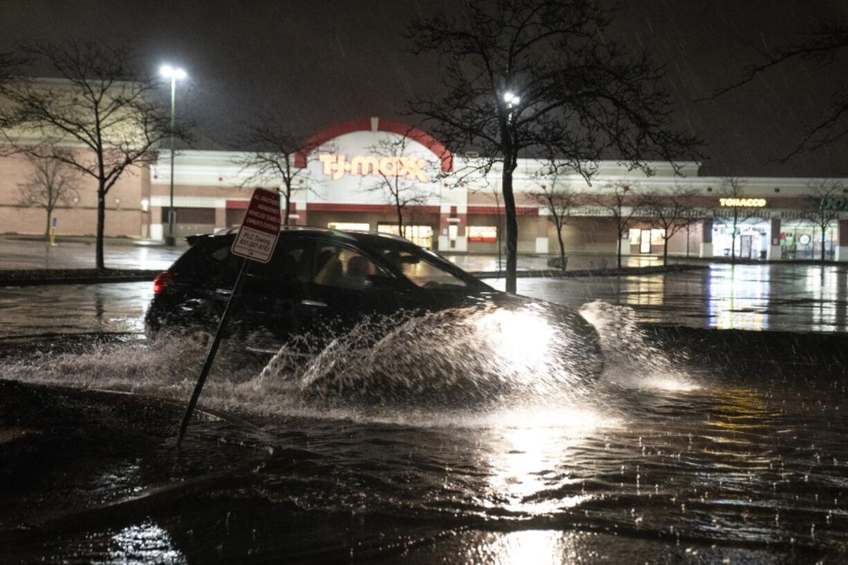 A vehicle drives through a flooded parking lot off of University Avenue in St. Paul, Minn., during severe weather, Wednesday, May 11, 2022.