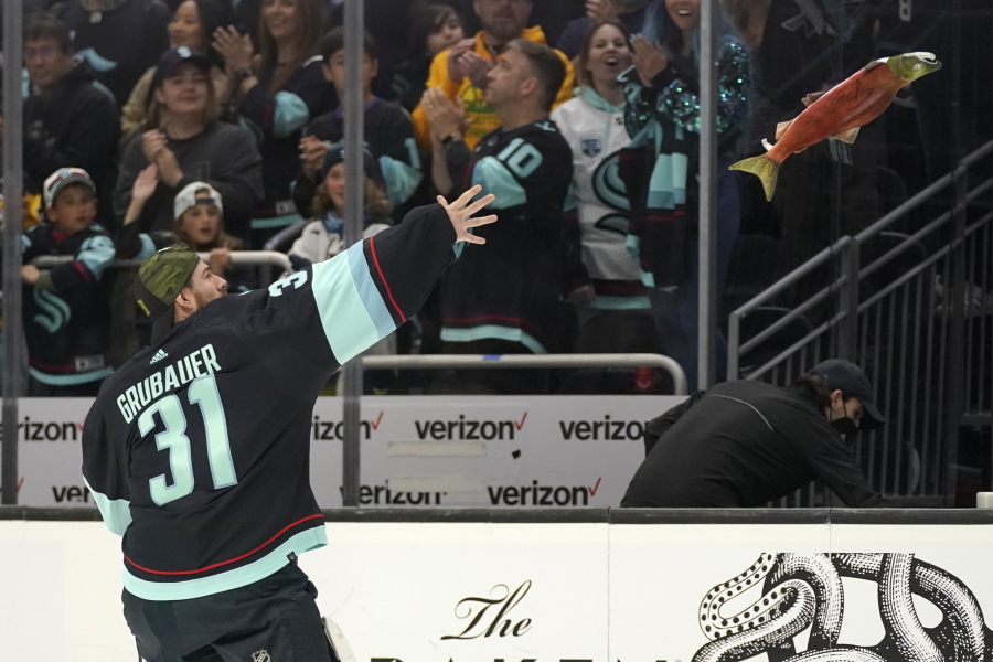 Seattle Kraken goaltender Philipp Grubauer tosses a stuffed salmon to fans after the team's NHL hockey game against the San Jose Sharks, Friday, April 29, 2022, in Seattle. The Kraken won 3-0. (AP Photo/Ted S.