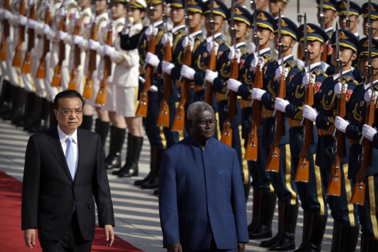 FILE - Chinese Premier Li Keqiang, left, and Solomon Islands Prime Minister Manasseh Sogavare review an honor guard during a welcome ceremony at the Great Hall of the People in Beijing, on Oct. 9, 2019.  China's Foreign Minister Wang will visit Solomon Islands this week in what the South Pacific nation's leader said was a "milestone" in his country's relationship with China, amid concerns over their security pact that could allow Chinese military personnel on the islands.