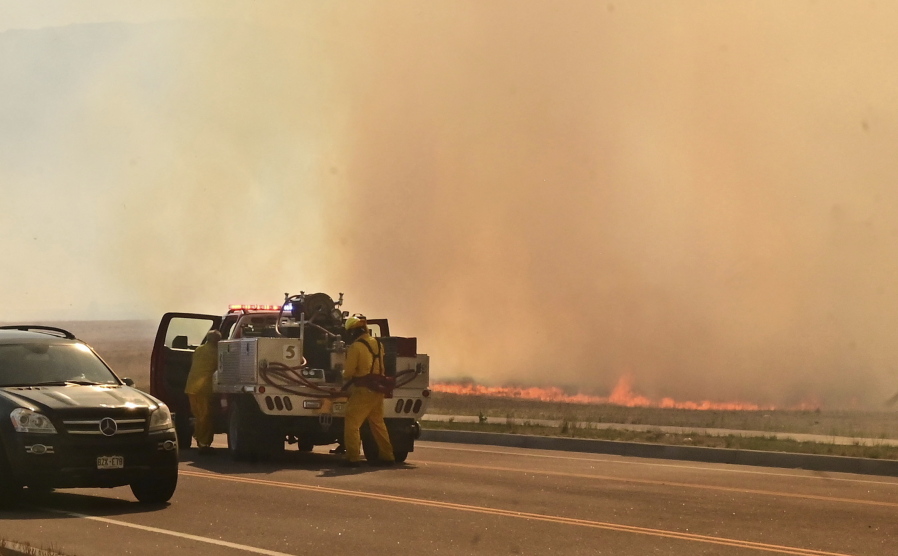 FILE - A firefighting crew arrives at the scene of a field on fire adjacent to the Amazon Distribution Center in Colorado Springs, Colo., on May 12, 2022. More than 5,000 firefighters are battling multiple wildland blazes in dry, windy weather across the Southwest. Evacuation orders remained in place Thursday, May 19, 2022, for residents near fires in Texas, Colorado and New Mexico.