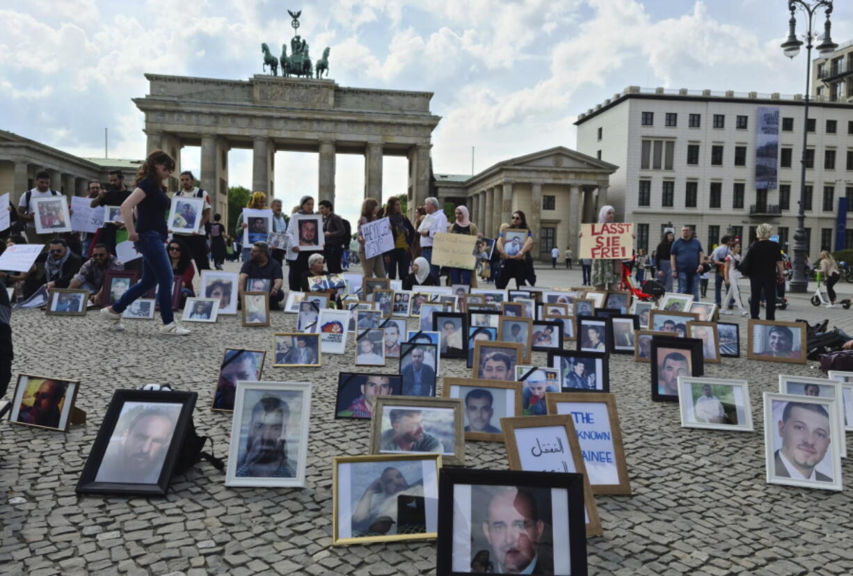 This photo provided by Syrian activist Wafaa Mustafa, shows families of Syrian detainees carrying photos of their detained the missing loved ones, as they demanding their freedom and the revealing of their fate and whereabouts during a sit-in, in Berlin Germany, on Saturday, May, 7, 2022. A newly released video taken in 2013 showed blindfolded men who were thrown into a large pit and shot dead by Syrian agents, who then set the bodies on fire. The video stirs new fears over the fate of tens of thousands who went missing during Syria's long-running conflict and serves as a grim reminder of the war's unpunished massacres, just as similar atrocities take place in Ukraine.