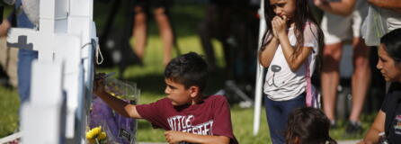 A child writes a message on a cross at a memorial site for the victims killed in this week's elementary school shooting in Uvalde, Texas, Thursday, May 26, 2022.