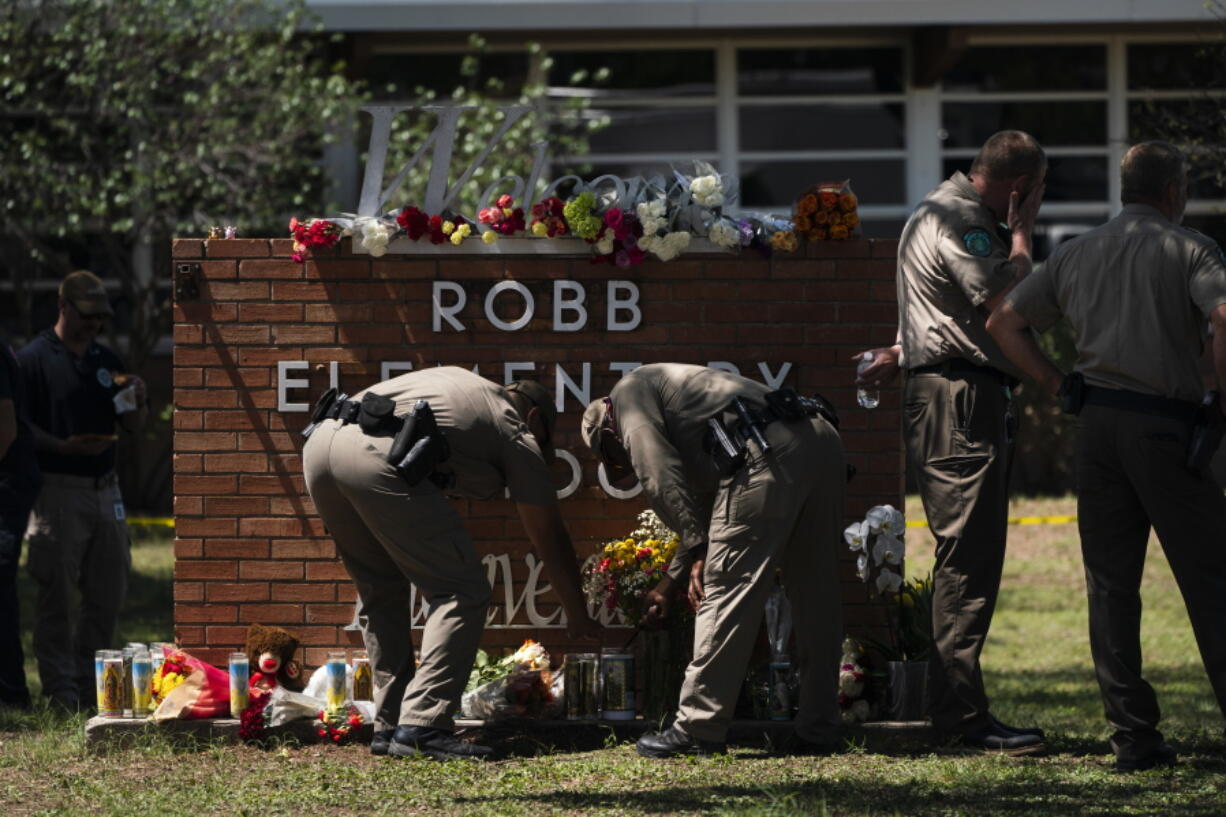 Two Texas Troopers light a candle at Robb Elementary School in Uvalde, Texas, Wednesday, May 25, 2022. Desperation turned to heart-wrenching sorrow for families of grade schoolers killed after an 18-year-old gunman barricaded himself in their Texas classroom and began shooting, killing several fourth-graders and their teachers. (AP Photo/Jae C.