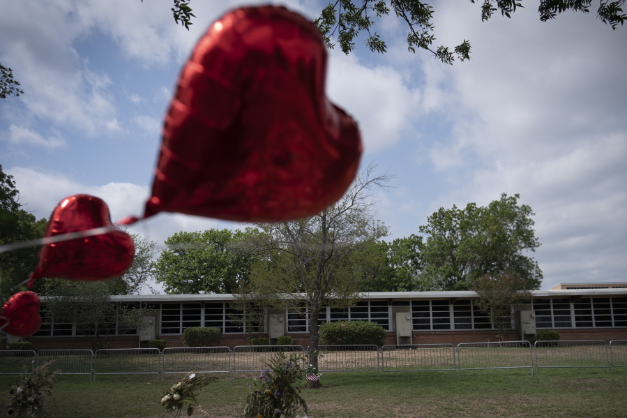 A heart shaped balloon flies decorating a memorial site outside Robb Elementary School in Uvalde, Texas, Monday, May 30, 2022. 19 children and two teachers were killed by an 18-year-old gunman at the school last week.