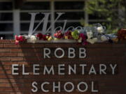 Flowers are placed around a welcome sign outside Robb Elementary School in Uvalde, Texas, Wednesday, May 25, 2022, to honor the victims killed in Tuesday's shooting at the school. Desperation turned to heart-wrenching sorrow for families of grade schoolers killed after an 18-year-old gunman barricaded himself in their Texas classroom and began shooting, killing several fourth-graders and their teachers. (AP Photo/Jae C.