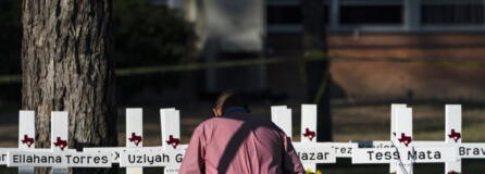 Pastor Daniel Myers kneels in front of crosses bearing the names of Tuesday's shooting victims while praying for them at Robb Elementary School in Uvalde, Texas, Thursday, May 26, 2022. (AP Photo/Jae C.
