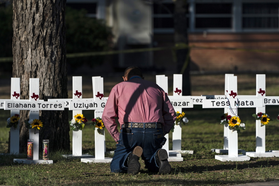Pastor Daniel Myers kneels in front of crosses bearing the names of Tuesday's shooting victims while praying for them at Robb Elementary School in Uvalde, Texas, Thursday, May 26, 2022. (AP Photo/Jae C.