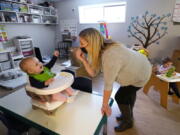FILE - Amy McCoy signs to a baby about food as a toddler finishes lunch behind at her Forever Young Daycare facility, Monday, Oct. 25, 2021, in Mountlake Terrace, Wash. According to a report released by the Centers for Disease Control and Prevention on Tuesday, May 24, 2022, U.S. births bumped up in 2021, but the number of babies born was still lower than before the coronavirus pandemic.
