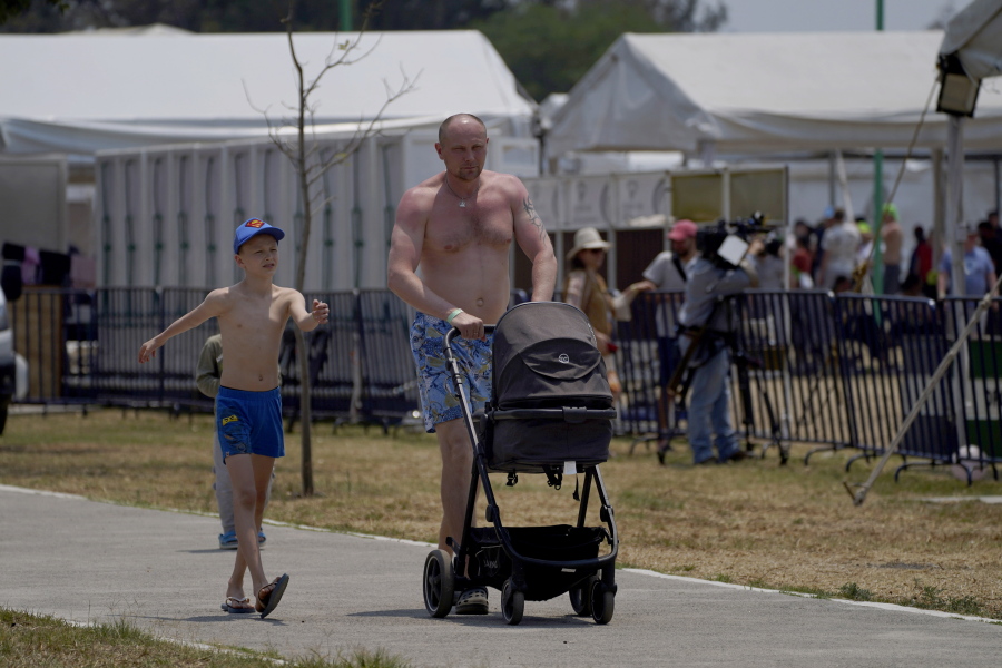 A Ukrainian refugee walks with his children at a camp in Utopia Park, Iztapalapa, Mexico City, Monday, May 2, 2022.