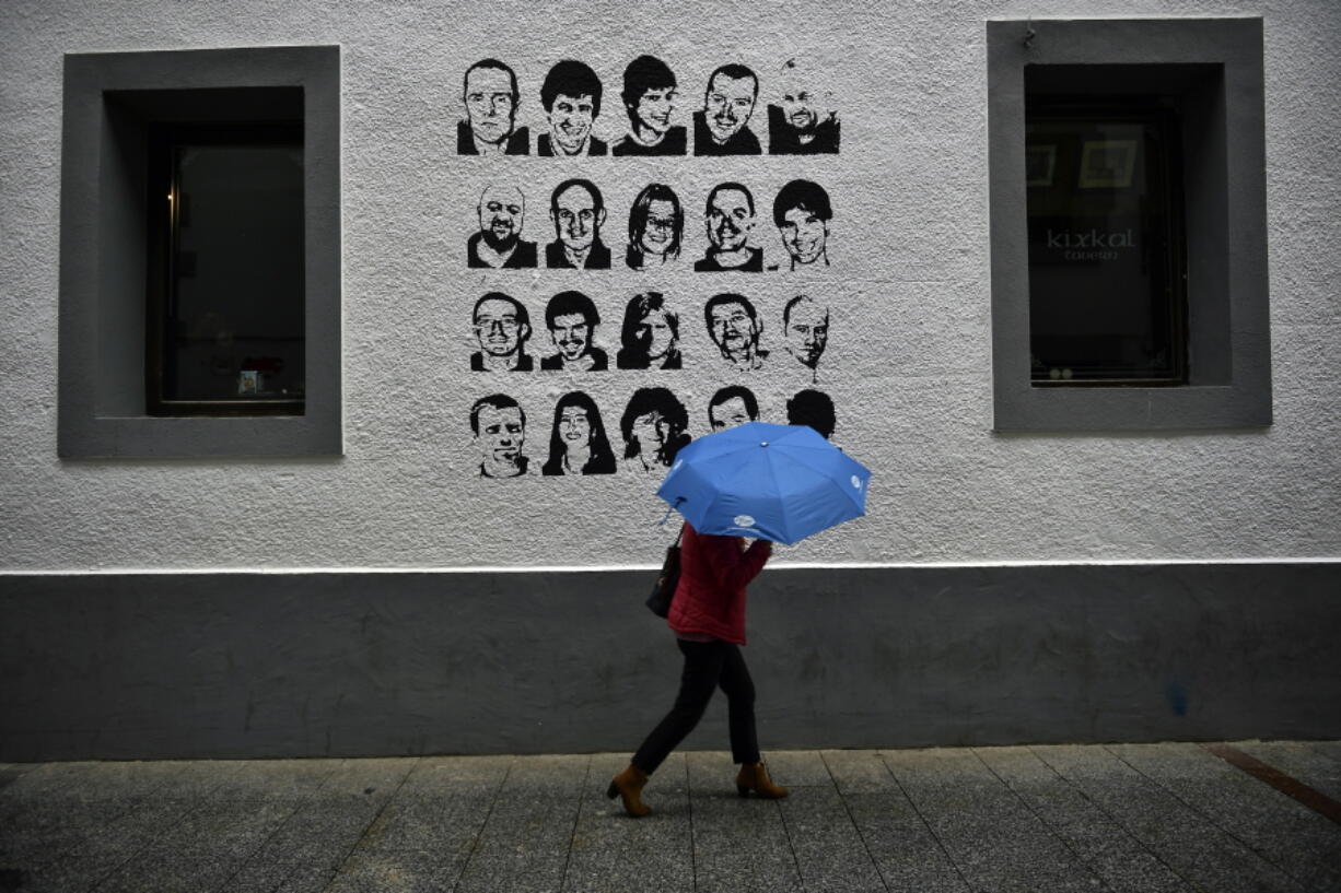 A woman shelters from the rain under an umbrella, while walking past a wall painted with portraits of prisoners of the Basque separatist armed group ETA, in the small village of Hernani, northern Spain, May 2, 2018. The United States is poised to remove five extremist groups, all believed to be defunct, from its list of foreign terrorist organizations. Several of these groups once posed significant threats, killing hundreds if not thousands of people across Asia, Europe and the Middle East. The organizations include the Basque separatist group ETA , the Japanese cult Aum Shinrikyo, the radical Jewish group Kahane Kach and two Islamic groups that have been active in Israel, the Palestinian territories and Egypt.