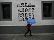 A woman shelters from the rain under an umbrella, while walking past a wall painted with portraits of prisoners of the Basque separatist armed group ETA, in the small village of Hernani, northern Spain, May 2, 2018. The United States is poised to remove five extremist groups, all believed to be defunct, from its list of foreign terrorist organizations. Several of these groups once posed significant threats, killing hundreds if not thousands of people across Asia, Europe and the Middle East. The organizations include the Basque separatist group ETA , the Japanese cult Aum Shinrikyo, the radical Jewish group Kahane Kach and two Islamic groups that have been active in Israel, the Palestinian territories and Egypt.