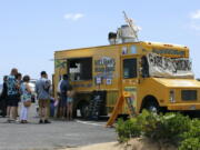 People line up at a food truck parked near Waikiki Beach in Honolulu, Monday, May 23, 2022. A COVID surge is under way that is starting to cause disruptions as schools wrap up for the year and Americans prepare for summer vacations. Case counts are as high as they've been since mid-February and those figures are likely a major undercount because of unreported home tests and asymptomatic infections. But the beaches beckoned and visitors have flocked to Hawaii, especially in recent months.