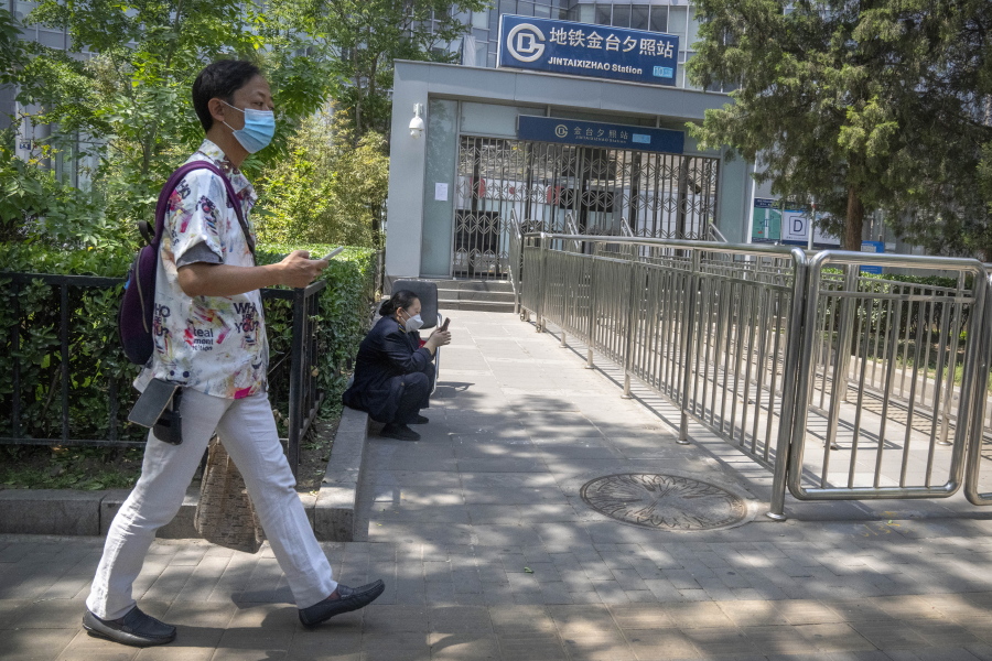 A man wearing a face mask walks past the closed exit of a subway station in Beijing, Wednesday, May 4, 2022. Beijing on Wednesday closed around 10% of the stations in its vast subway system as an additional measure against the spread of coronavirus.
