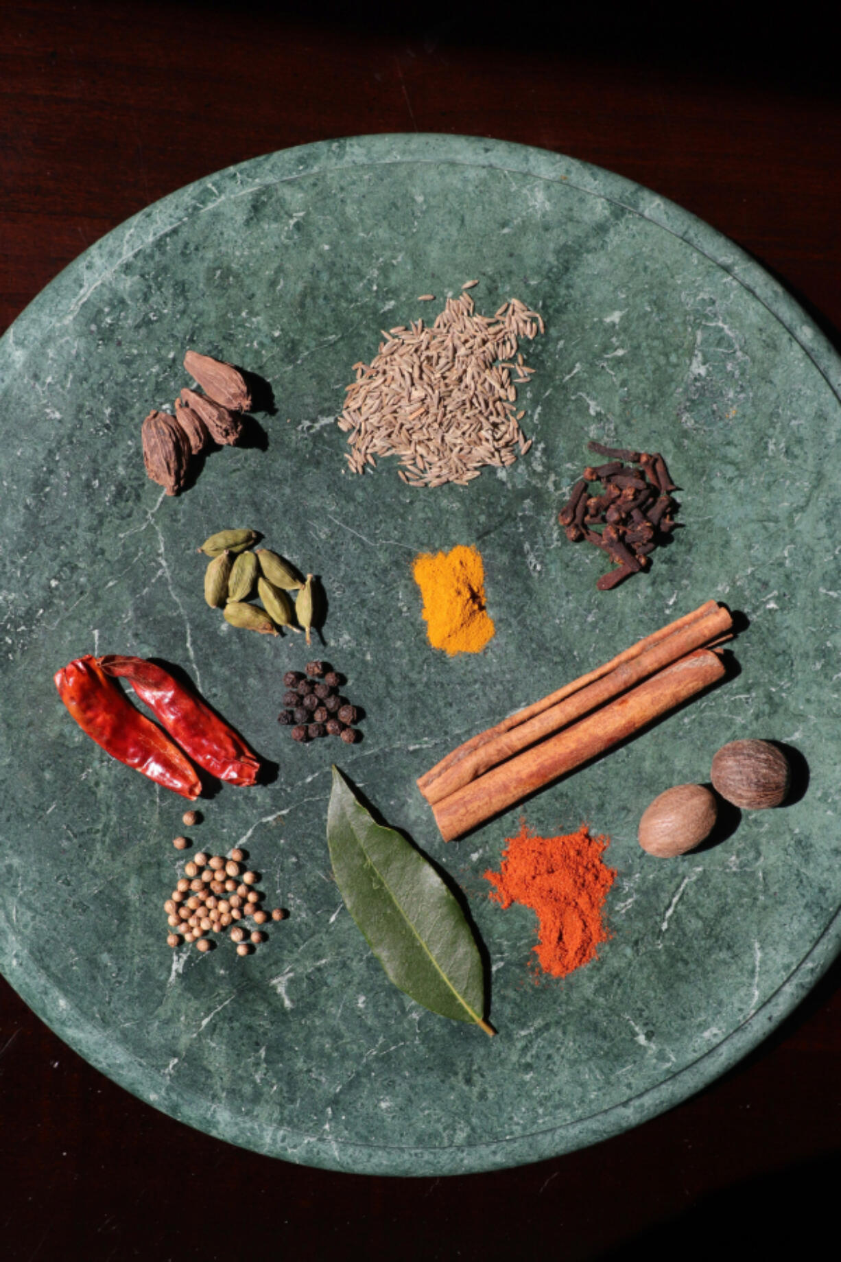 Curry comes from different regions of the world and can be made with ingredients such as: top, from left: black cardamom pods, cumin seeds; second row: green cardamom pods, ground turmeric, cloves; third row: dried red peppers, black peppercorns, cinnamon sticks; fourth row: coriander seeds, bay leaf, paprika, nutmeg. (Photos by Hillary Levin/St.