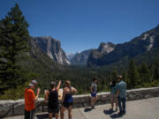 Visitors walk to the Tunnel View lookout in Yosemite Valley at Yosemite National Park, Calif., on July 8, 2020.