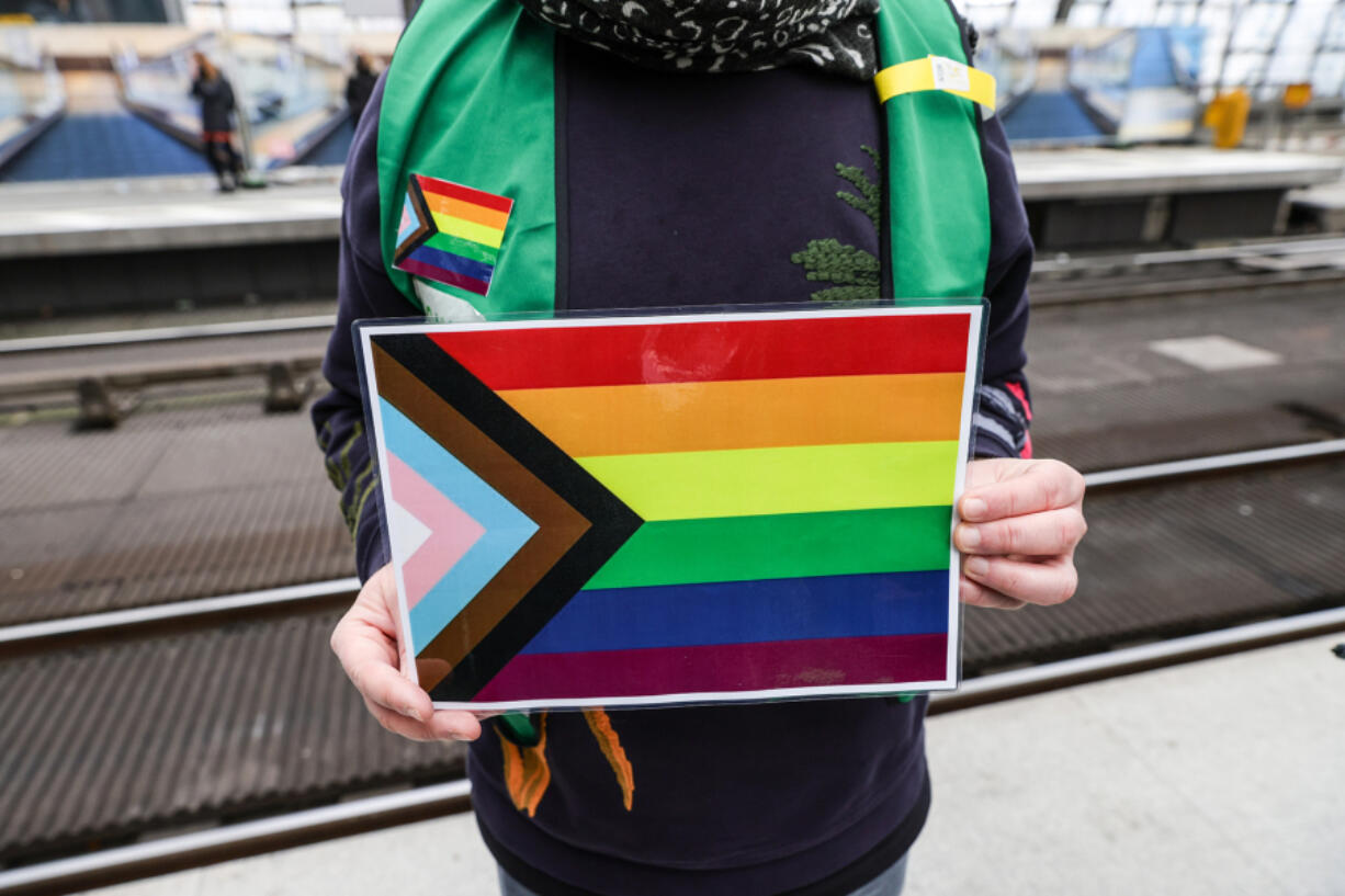 A volunteer holds a "Progress Pride Flag" on March 8 at Hauptbahnhof main railway station in Berlin, Germany.