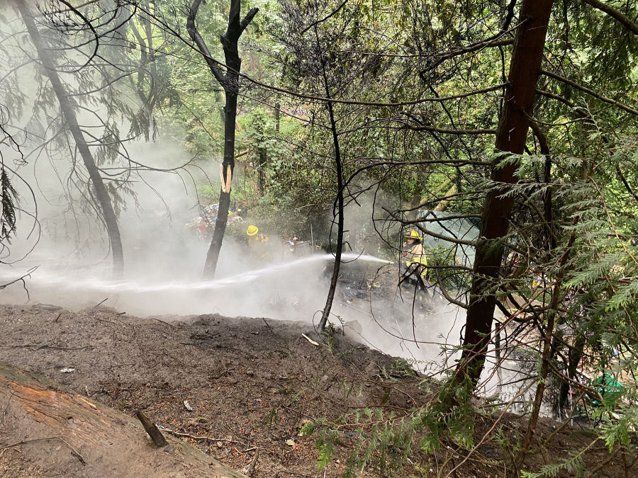 Firefighters extinguish a hillside fire Tuesday morning in Hazel Dell that Clark County Fire District 6 says started in a large homeless encampment before spreading to trees. The department said one person suffered non-life threatening injuries.