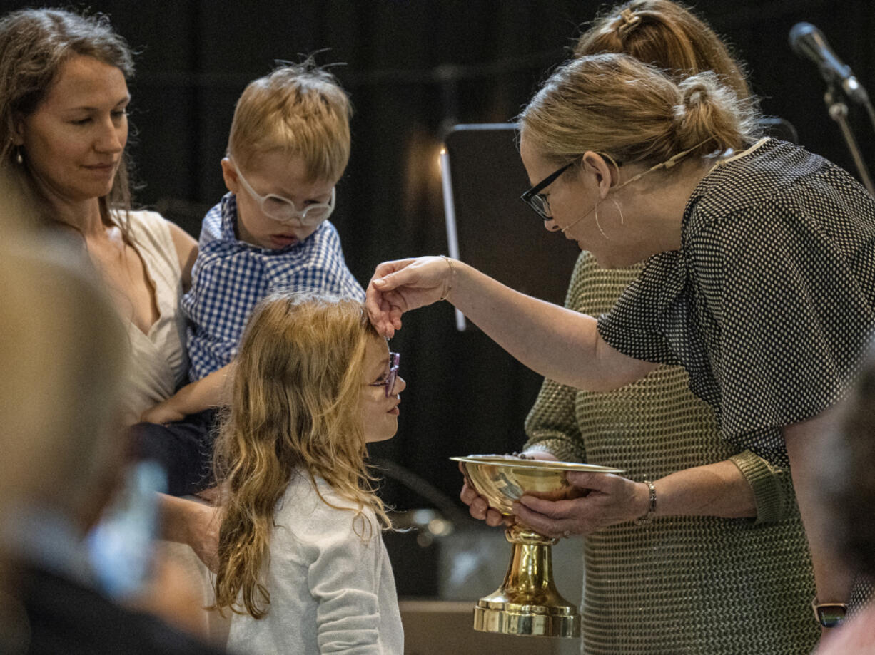 Pastor Sara Wilhem Garbers blesses Fiona Watson while Erin Watson holds son Julian during a baptism ceremony June 12 at Meetinghouse Church in Edina, Minn.