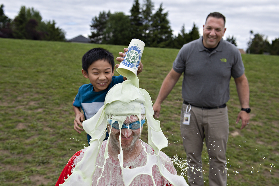 Fifth grader James Saldua, from left, dumps a cup full of homemade slime on his physical education teacher, Devin Cast, as Associate Principal Casey Greco looks on at Felida Elementary School on Monday afternoon. Students and staff were celebrating a successful fundraiser for the American Heart Association's Kids Heart Challenge. James was one of 10 students who raised over $500.
