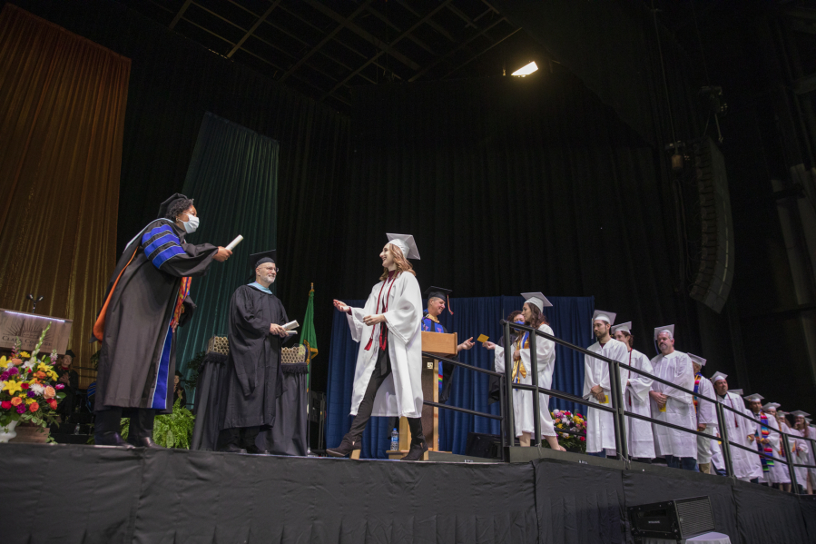 Graduates cross the stage to receive their diplomas at the Clark College commencement ceremony.