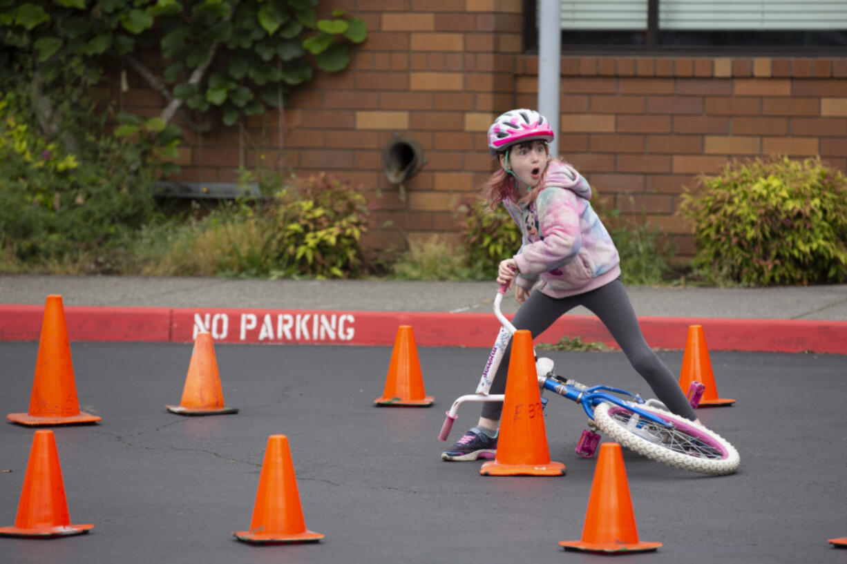 Arwen English, 7, of Vancouver, reacts after her bike tips over while navigating the obstacle course Saturday during the Police Activities League of Southwest Washington's first annual Bike Rodeo at Evergreen High School. The obstacle course was a culmination of the safety skills children learned at booths as they made their way through the parking lot to the course.