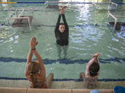 Swim teacher Jane Twinkel, facing, helps young students with their form during a lesson at Kids Club Fun & Fitness in Salmon Creek on Tuesday morning. Kids Club and other facilities offering summer programs have had a hard time hiring workers in a tight labor market. Lifeguards especially are in short supply.