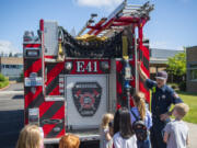 Camas-Washougal Fire Department firefighter Trevor Guay shows off a fire truck to a group of kids Wednesday at Hellen Baller Elementary.