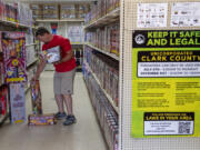 A sign at Blackjack Fireworks in Hazel Dell promotes safety as store manager Jeremy Mohney looks through some of the holiday items on display Thursday afternoon. Fireworks go on sale Tuesday.