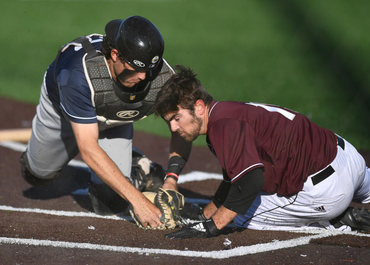 Pickles catcher Michael Campanga, left, tags out Raptors baserunner Austin Caviness at home plate Tuesday, June 28, 2022, during a game between the Ridgefield Raptors and the Portland Pickles at the Ridgefield Outdoor Recreation Complex.