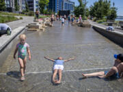 Vancouver kids Addy Bugge, 3, from left, joins Elizabeth White Eyes, 7, and Kai Sabanovic, 6, to beat the heat in the water feature at The Waterfront Vancouver on Monday afternoon. Forecasters predict cooler weather on the way.