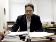 Carl Macpherson, executive director at Metropolitan Public Defender, examines the file in a double murder case that was recently pushed back for trial in his office in Portland on May 5, 2022. Macpherson says his firm of 90 public defenders recently stopped taking certain types of new criminal cases for a month in two local courts because they had so many cases that the attorneys were violating their ethical obligations to clients. A post-pandemic glut of delayed cases has exposed shocking constitutional landmines impacting defendants and crime victims alike in Oregon, where an acute shortage of public defenders has even led judges to dismiss serious cases.