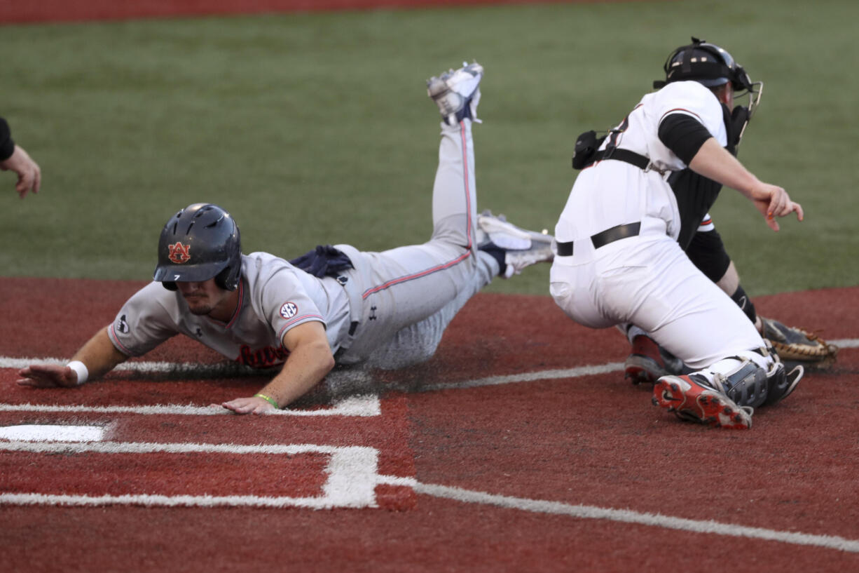 Auburn's Cole Foster slides past Oregon State's Gavin Logan to score during the third inning of an NCAA college baseball tournament super regional game Saturday, June 11, 2022, in Corvallis, Ore.