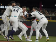 Seattle Mariners' Dylan Moore, center, is mobbed by teammates after he hit a single off Boston Red Sox closing pitcher Hansel Robles to score Sam Haggerty with the winning run during the ninth inning of a baseball game Saturday, June 11, 2022, in Seattle. The Mariners won 7-6. (AP Photo/Ted S.