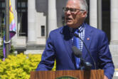 Washington state Gov. Jay Inslee addresses a gathering before raising the LGBTQ Pride Celebration flag seen behind him during a noon ceremony at the Capitol Campus flag circle, Tuesday, June 21, 2022, in Olympia, Wash. A variety of events celebrating the LGBTQ community statewide have taken place and are also scheduled through the month of June.