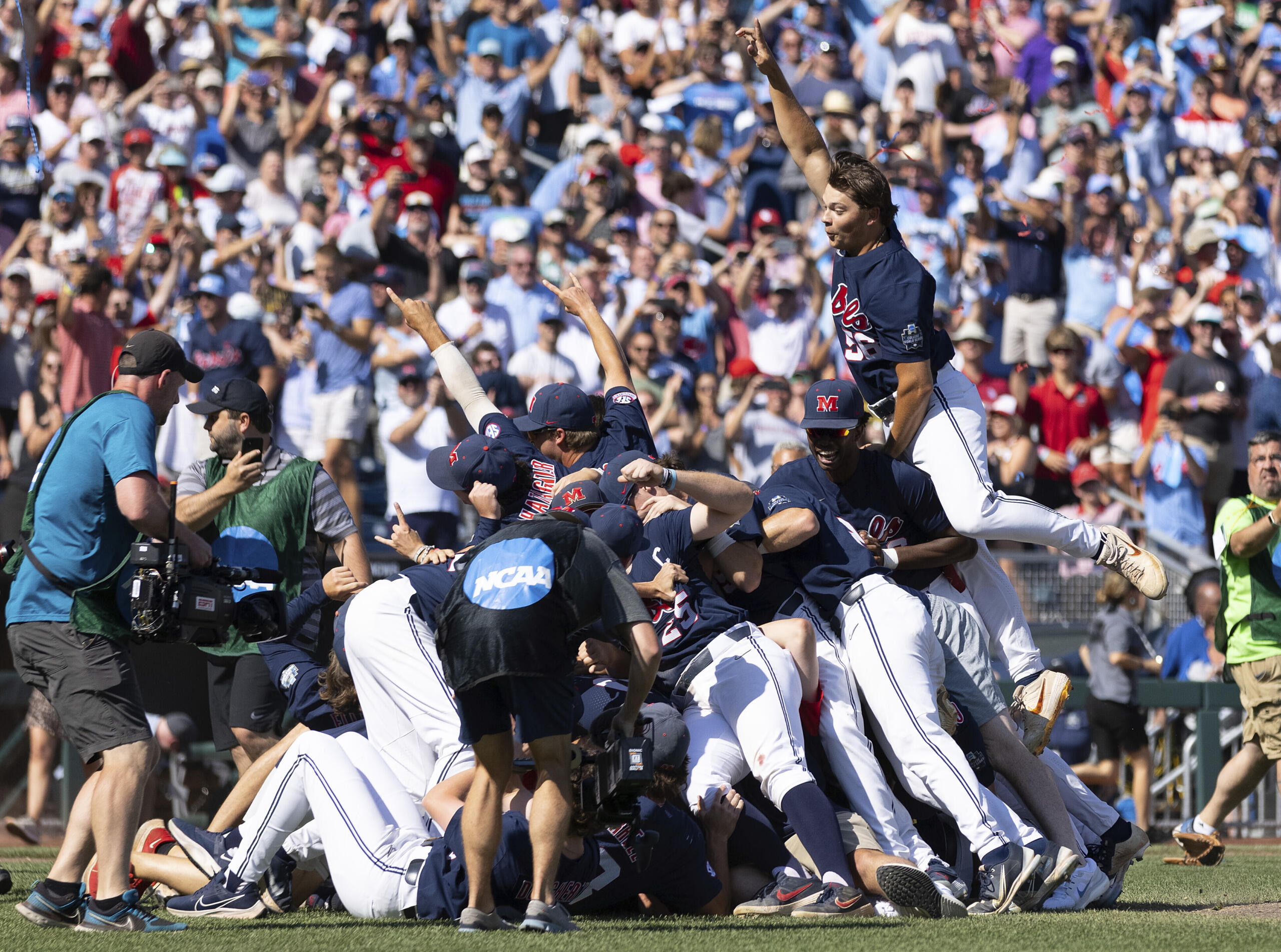 Mississippi's Jack Washburn, right, leaps on top of the team pile in celebration of their 4-2 victory over Oklahoma in Game 2 of the NCAA College World Series baseball finals, Sunday, June 26, 2022, in Omaha, Neb. Mississippi defeated Oklahoma 4-2 to win the championship. (AP Photo/Rebecca S.