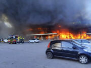 In this image made from video provided by Ukrainian State Emergency Service, firefighters work to extinguish a fire at a shopping center burned after a rocket attack in Kremenchuk, Ukraine, Monday, June 27, 2022.