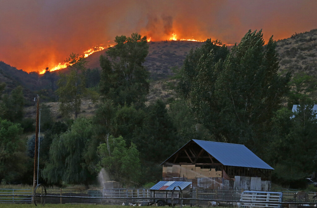 Flames and smoke rise on a ridge line above a ranch on Twisp River Road in Twisp, Wash., Wednesday, Aug. 19, 2015. Authorities on Wednesday afternoon urged people in the north-central Washington town to evacuate because of a fast-moving wildfire. (AP Photo/Ted S.