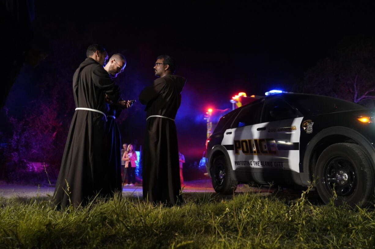Priests gather near the scene where officials say dozens of people have been found dead and multiple others were taken to hospitals with heat-related illnesses after a semitrailer containing suspected migrants was found, Monday, June 27, 2022, in San Antonio.
