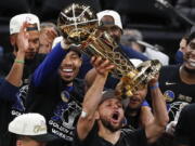 Golden State Warriors guard Stephen Curry, center, holds up the Larry O'Brien Championship Trophy with teammates after defeating the Boston Celtics in Game 6 of basketball's NBA Finals, Thursday, June 16, 2022, in Boston.