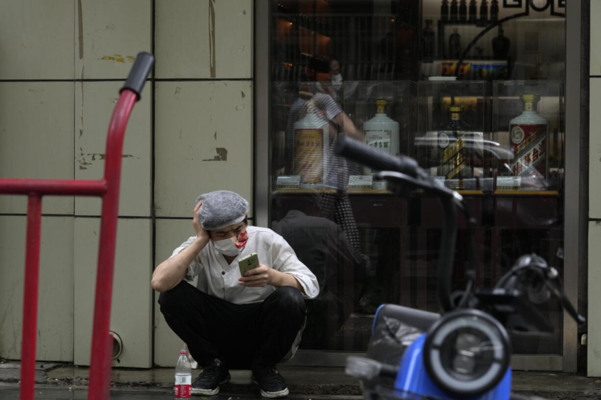 A restaurant cook wearing a mask takes a break out on the sidewalk, Monday, June 27, 2022, in Beijing.
