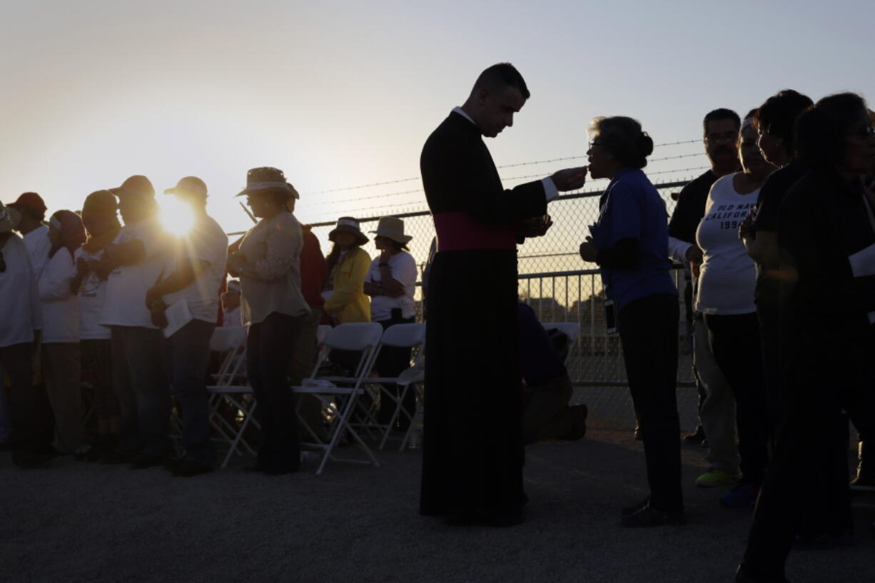 FILE - Migrants watching Pope Francis' Mass in Juarez, Mexico, from a levee along the banks of the Rio Grande in El Paso, Texas, take part in Communion, Wednesday, Feb. 17, 2016. According to a poll from The Associated Press-NORC Center for Public Affairs Research conducted in mid-May 2022, only 31% of lay Catholics agree that politicians supporting abortion rights should be denied Communion, while 66% say they be allowed access to the sacrament.