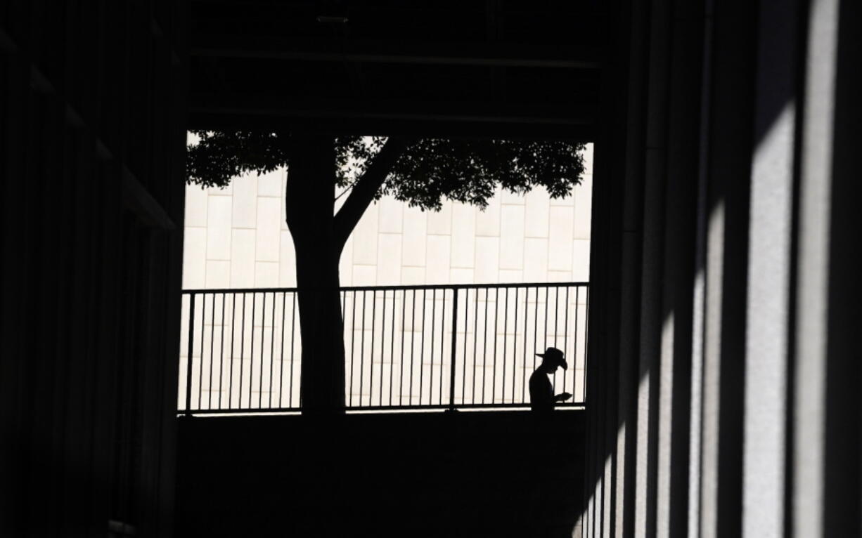 FILE - A person is silhouetted against a wall as they look down at their cell phone outside the Clara Shortridge Foltz Criminal Justice Center on July 29, 2021, in Los Angeles. With abortion now or soon to be illegal in over a dozen states and severely restricted in many more, Big Tech companies that vacuum up personal details of their users are facing new calls to limit that tracking and surveillance. One fear is that law enforcement or vigilantes could use those data troves against people seeking ways to end unwanted pregnancies.