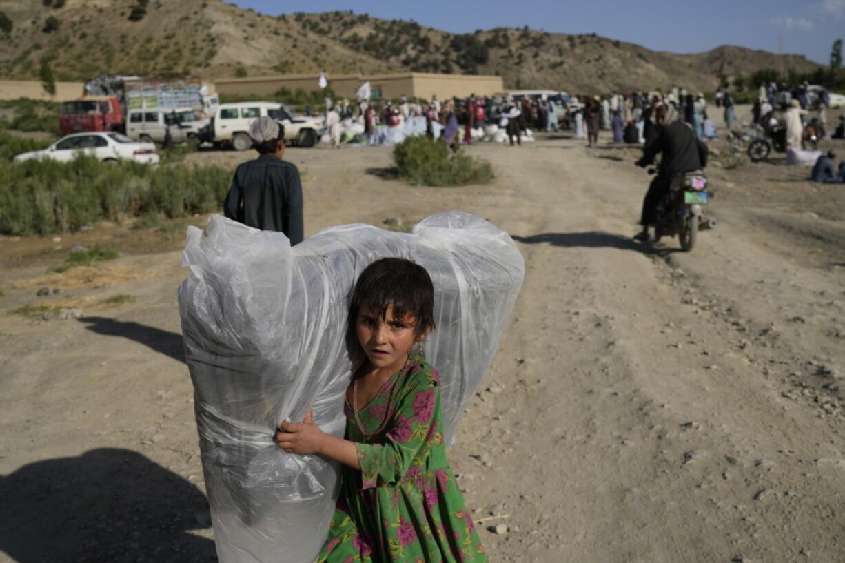 Afghan girl carries a donated matrace after an earthquake in Gayan village, in Paktika province, Afghanistan, Friday, June 24, 2022. A powerful earthquake struck a rugged, mountainous region of eastern Afghanistan early Wednesday, flattening stone and mud-brick homes in the country's deadliest quake in two decades, the state-run news agency reported.