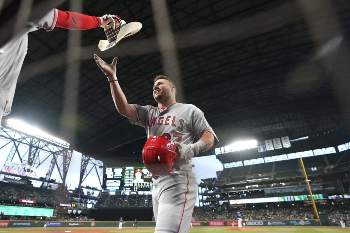 Los Angeles Angels' Mike Trout reaches for a cowboy hat as he walks to the dugout after hitting a solo home run against the Seattle Mariners during the third inning of the second baseball game of a doubleheader Saturday, June 18, 2022, in Seattle. (AP Photo/Ted S.